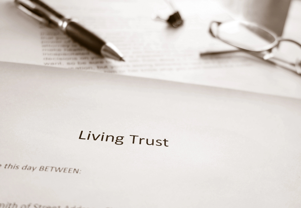 close-up of a living trust document on a desk with a pen and glasses, representing trust creation and estate planning.
