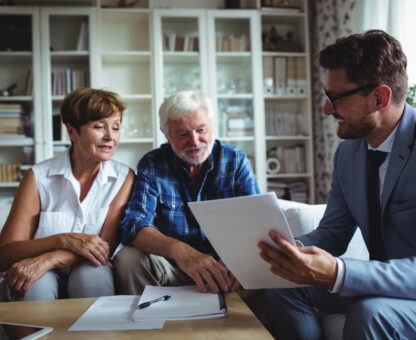 estate planning attorney reviewing legal documents with an older couple in their home