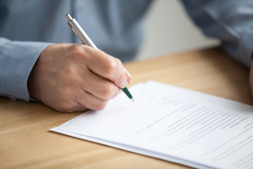 hand signing an estate planning document on a deskm representing formal legal decision-making