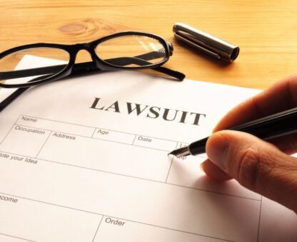 Person signing legal paperwork labeled lawsuit while considering how can I protect my assets in a lawsuit.