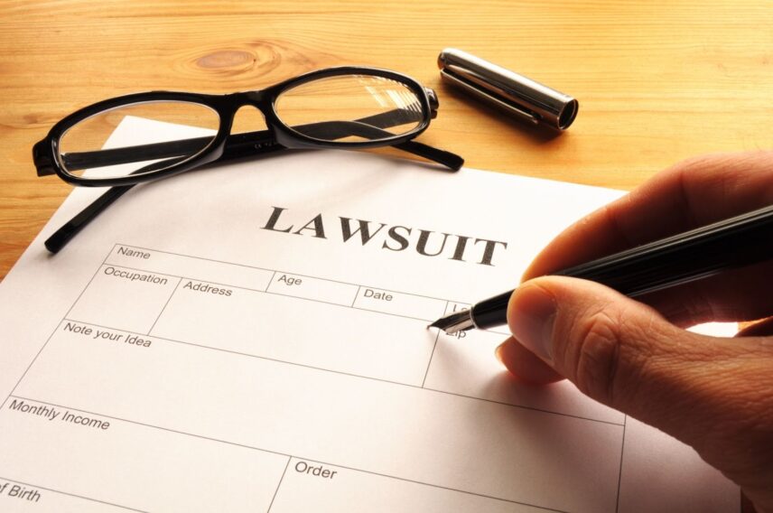 Person signing legal paperwork labeled lawsuit while considering how can I protect my assets in a lawsuit.