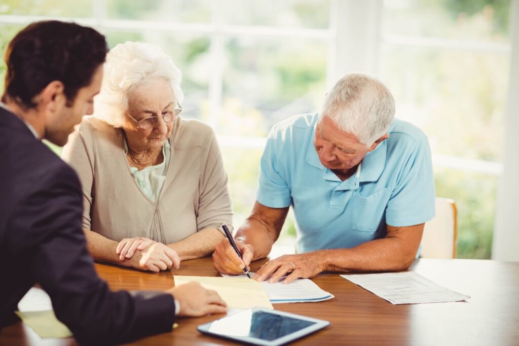 Older couple meeting with estate planning attorney and signing legal documents for wills, trusts, and asset protection.