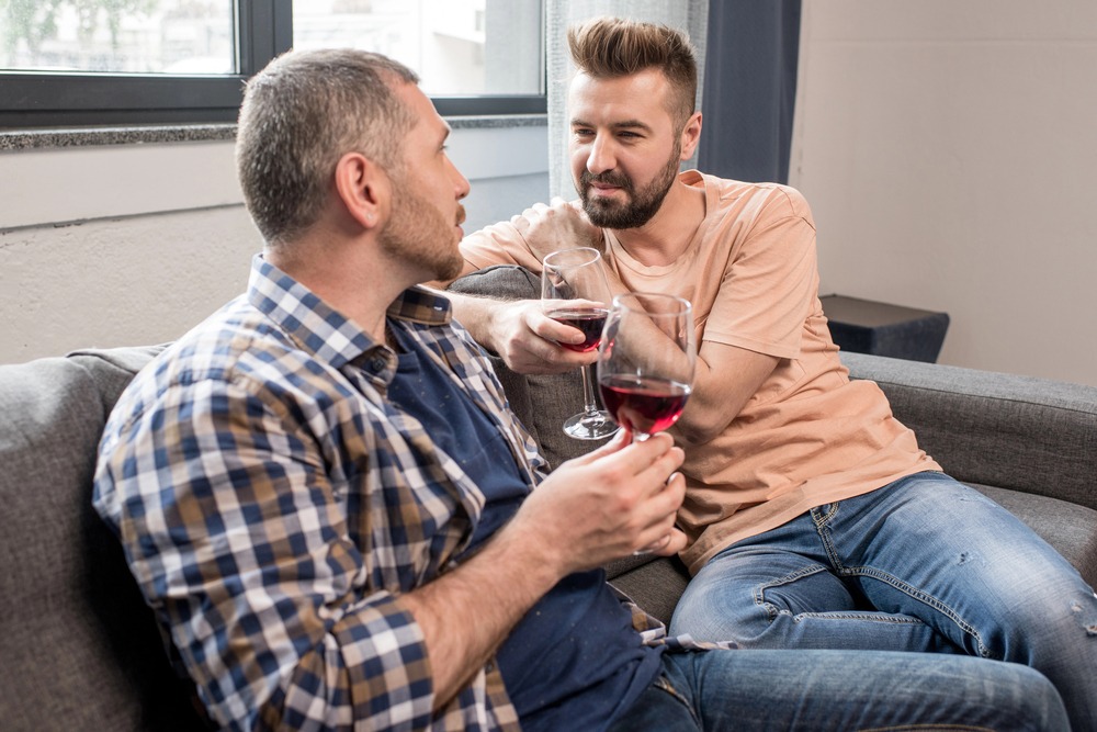 gay couple drinking wine on couch